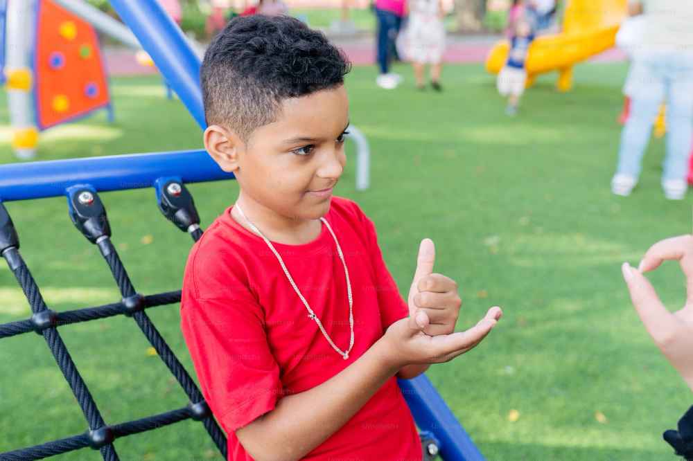 Niño realizando lengua de signos en un parque accesible