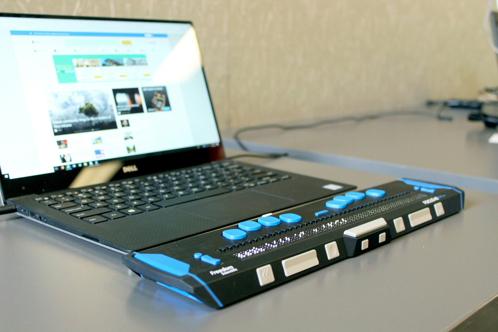 Ordenador portátil con una línea braille y teclas de navegación, mostrando tecnología de apoyo para la accesibilidad digital.